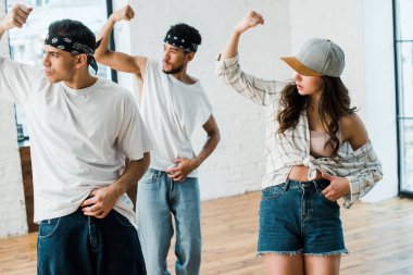 selective focus of multicultural dancers gesturing while dancing hip-hop in dance studio 