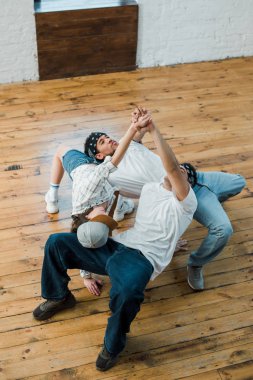 overhead view of multicultural dancers holding hands while posing in dance studio 