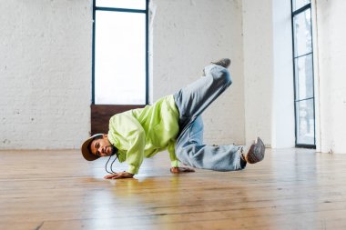 trendy african american man in cap breakdancing in dance studio  clipart