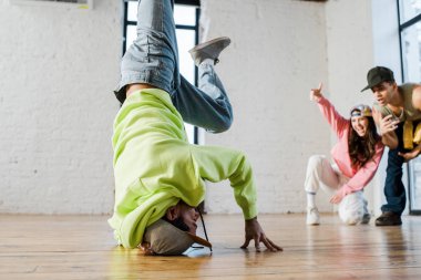 selective focus of african american dancer breakdancing near emotional man and woman clipart