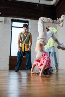 selective focus of girl doing handstand while breakdancing near multicultural men 