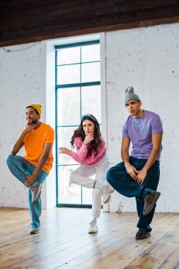 stylish woman and multicultural men breakdancing