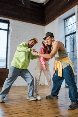 young woman looking at stylish multicultural men bumping fists