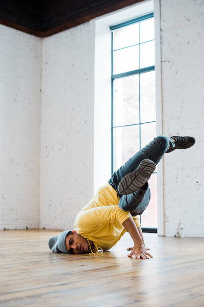 stylish man in hat breakdancing in dance studio 