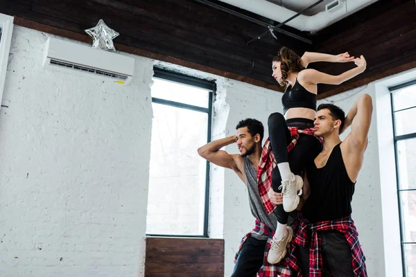 Fuertes Hombres Multiculturales Sosteniendo Mujer Mientras Posan Estudio Danza —  Fotos de Stock