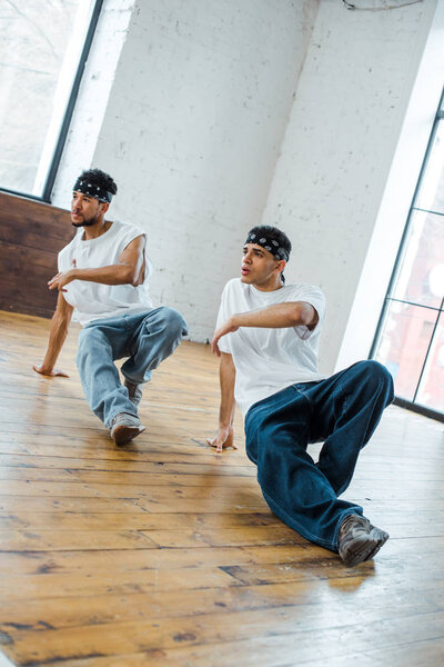 handsome multicultural men in headbands dancing hip-hop