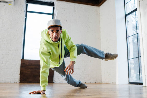 young african american man in cap breakdancing in dance studio 