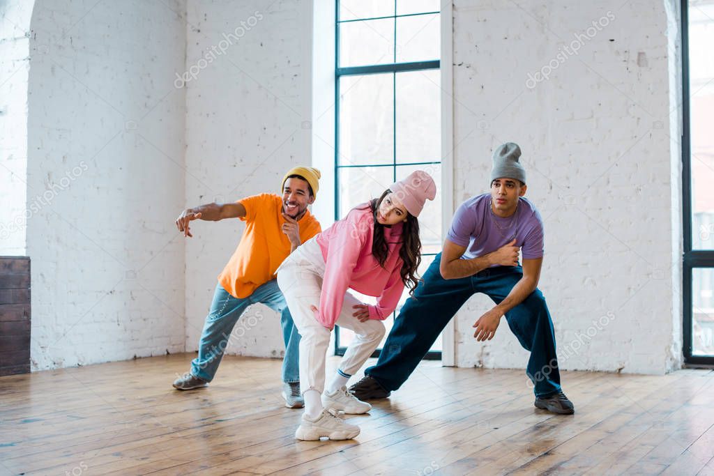 young multicultural dancers in hats breakdancing