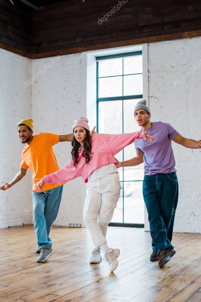 young multicultural dancers with outstretched hands breakdancing
