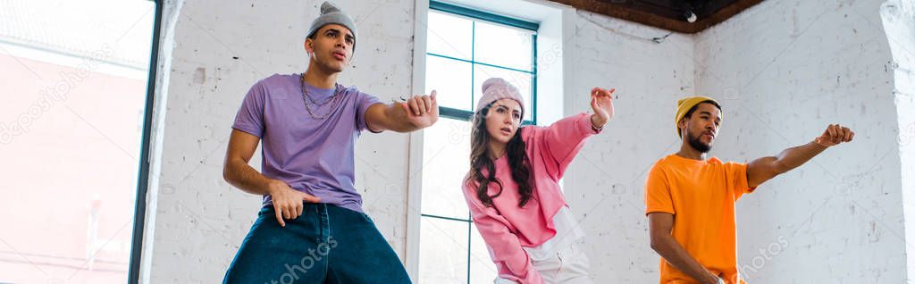 panoramic shot of multicultural men gesturing while breakdancing with attractive girl 