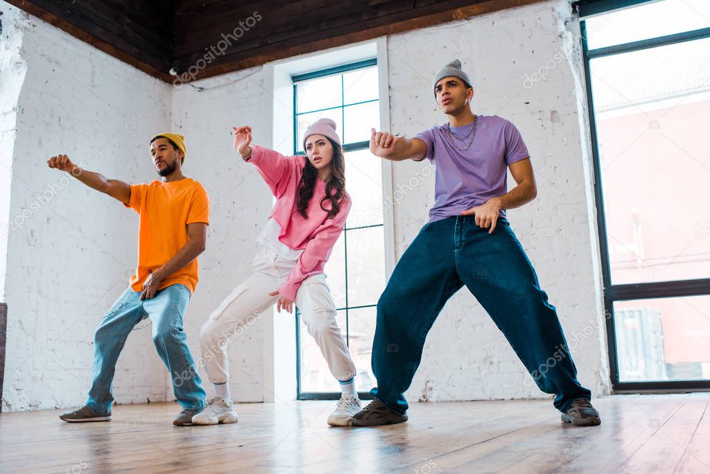 handsome multicultural men gesturing while breakdancing with attractive girl 