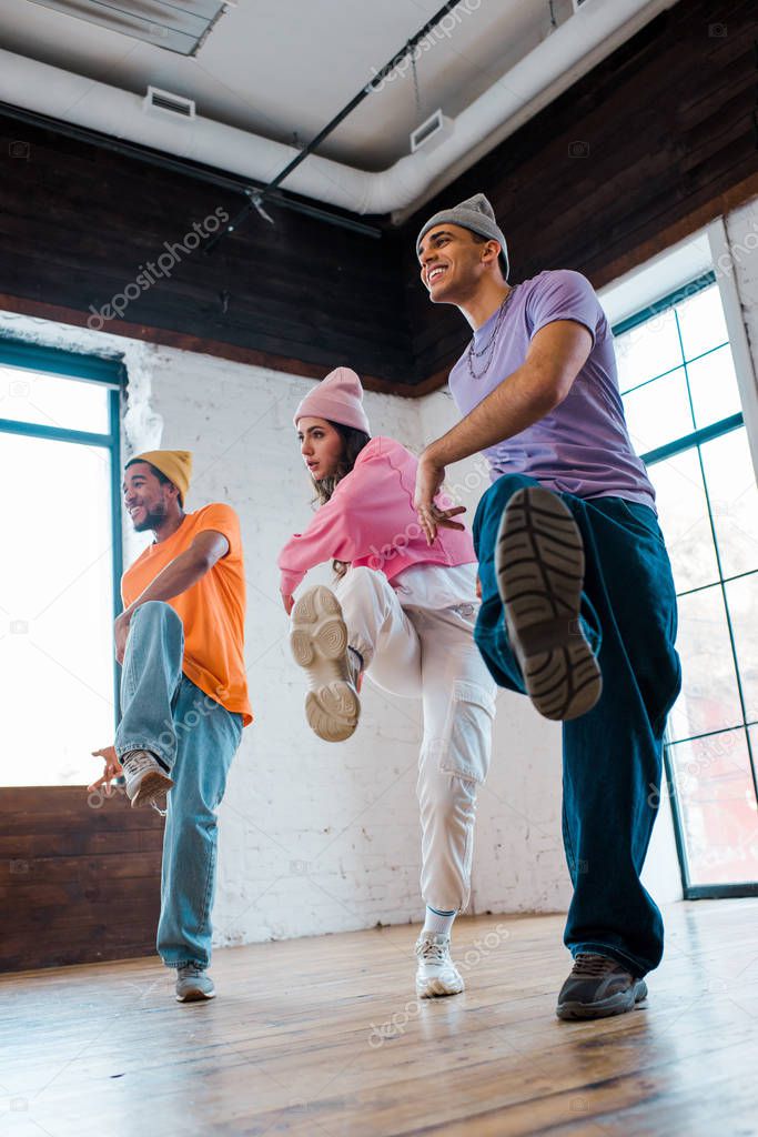 selective focus of handsome multicultural men in sneakers breakdancing with beautiful girl 