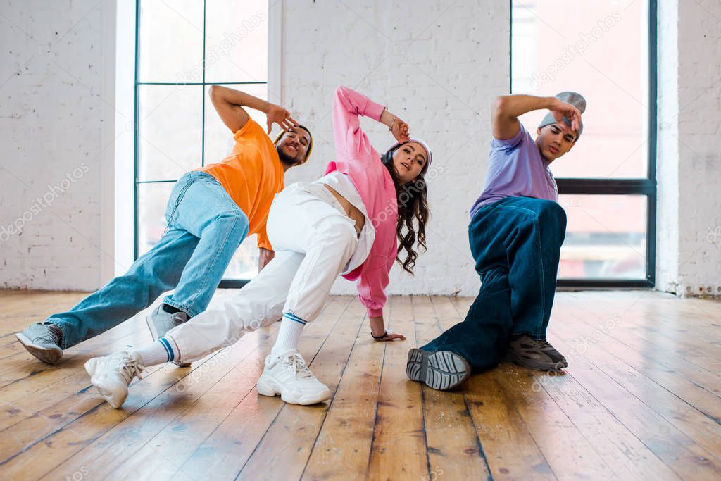 stylish multicultural men breakdancing with pretty young woman 