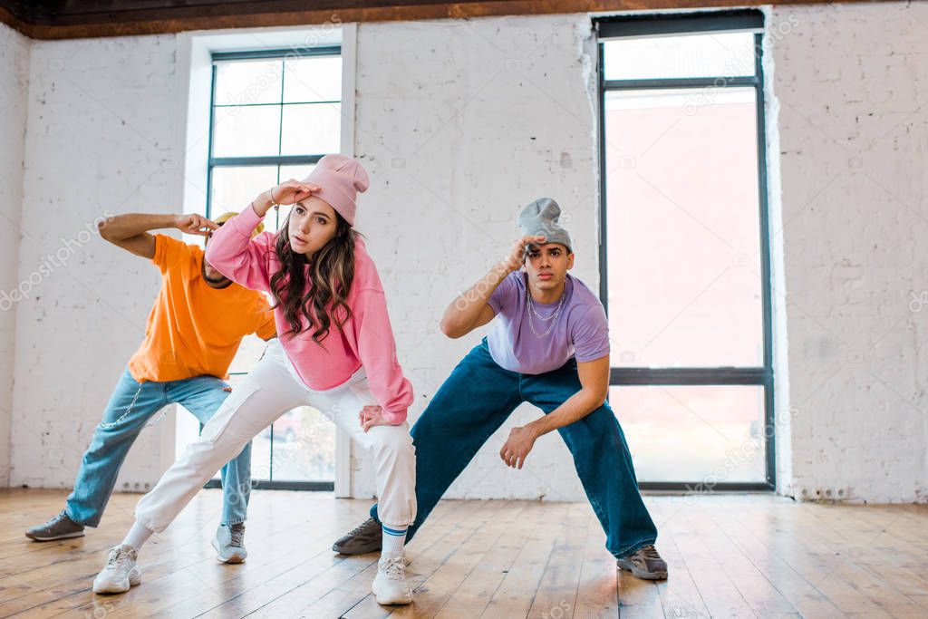 stylish girl breakdancing with multicultural men in hats 