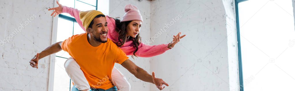 panoramic shot of attractive girl with outstretched hands breakdancing with african american man in hat 