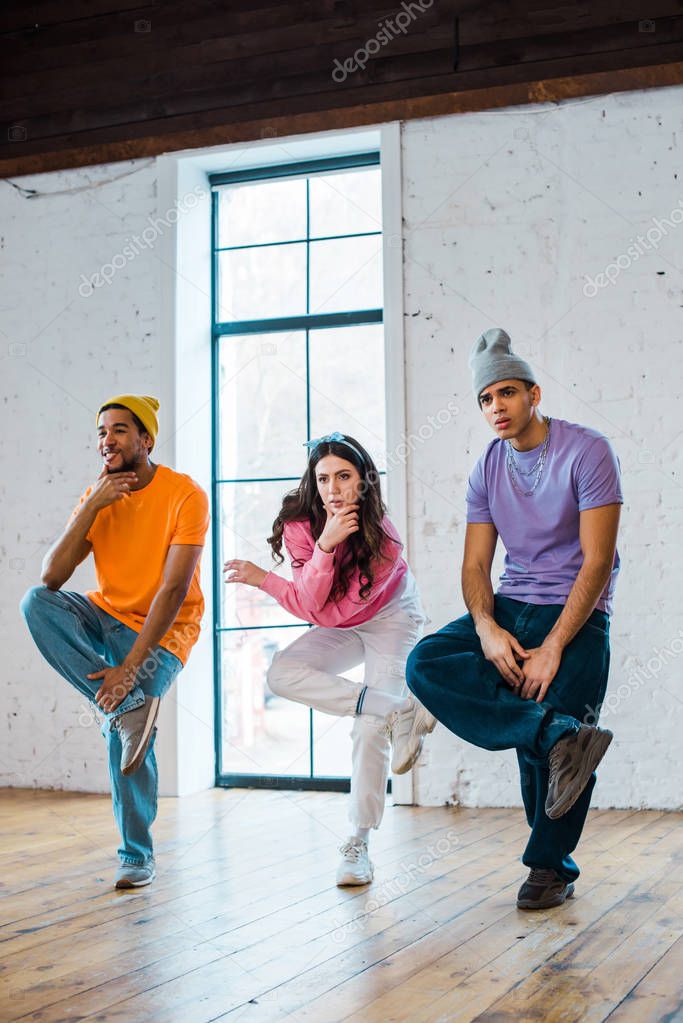 stylish woman and multicultural men breakdancing