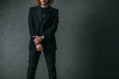 Gri duvarın yanında siyah takım elbiseli şık bir işadamının...