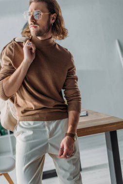 Zarif modaya uygun bir iş adamı ceketini tutuyor ve başka yere bakıyor.