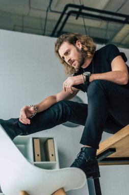 Masada poz veren siyah kıyafetli modaya uygun iş adamının düşük açılı görüntüsü