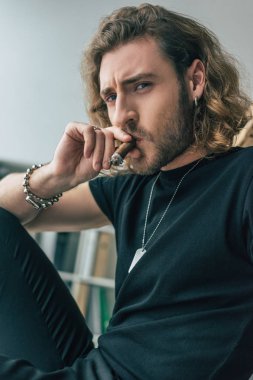 Ofiste puro içen siyah kıyafetli şık bir iş adamı.