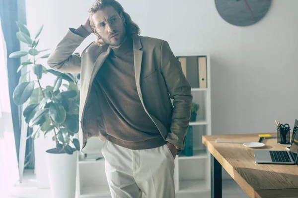 Elegante Hombre Negocios Moda Posando Con Mano Bolsillo Cerca Escritorio — Foto de Stock