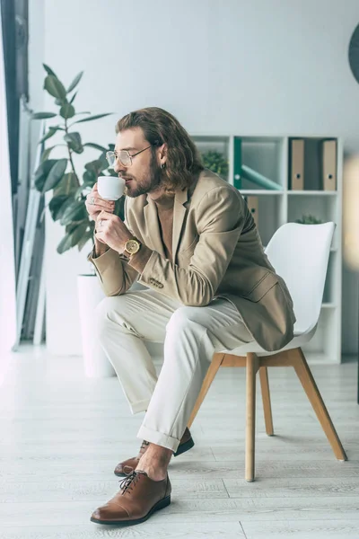 Eleganter Geschäftsmann Trinkt Kaffee Auf Stuhl Büro — Stockfoto