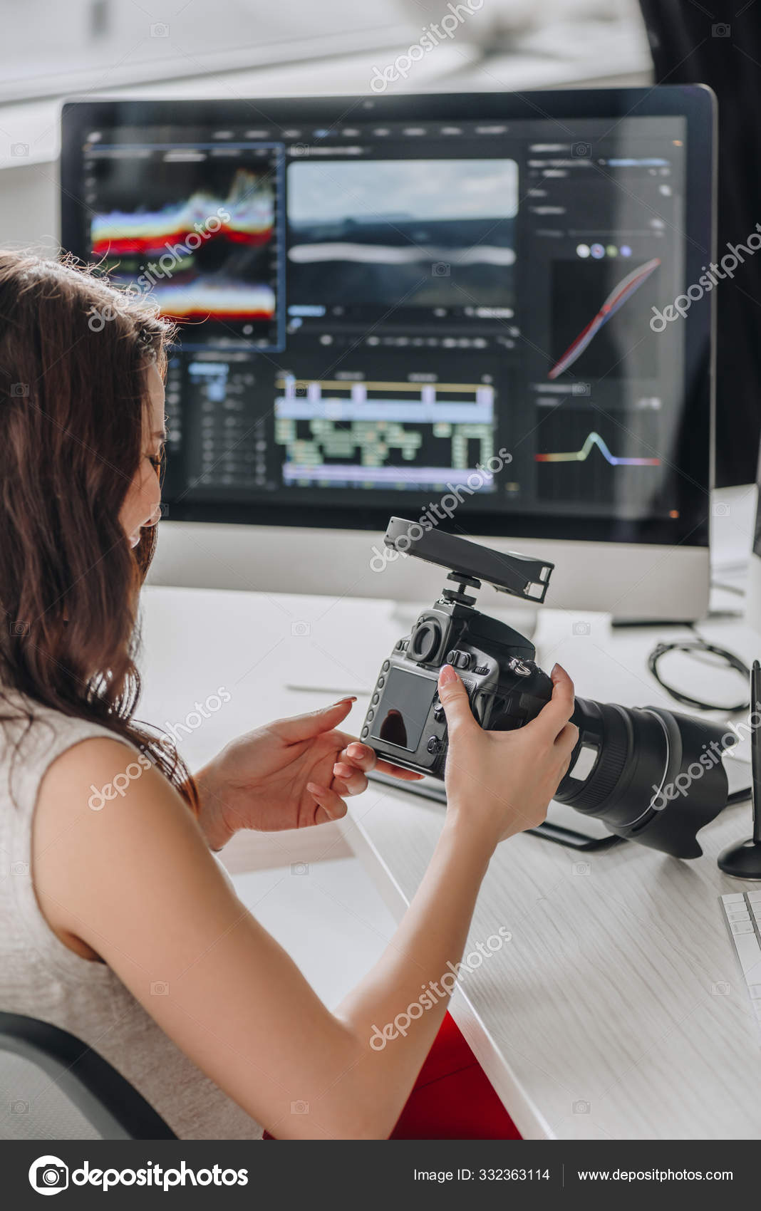 Редактор Держит Цифровую Камеру Возле Стола Мониторами Компьютера.