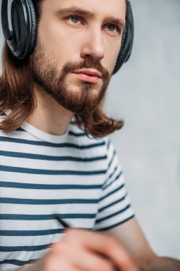 selective focus of handsome bearded editor listening music in headphones  clipart
