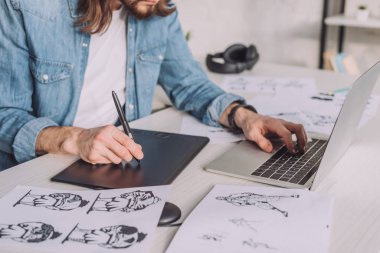 cropped view of animator using gadgets near sketches  clipart