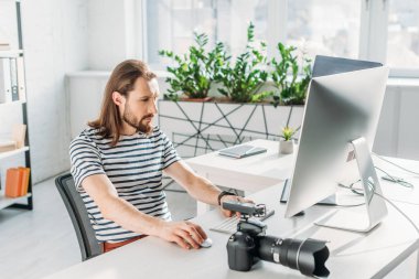 bearded editor working near digital camera in studio  clipart