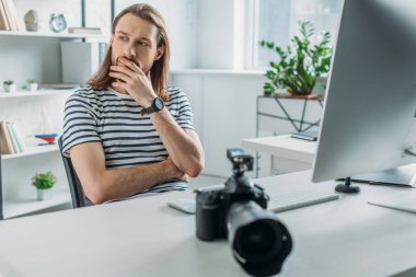 Dijital kameranın yanında düşünen düşünceli sanat editörünün seçici odağı 