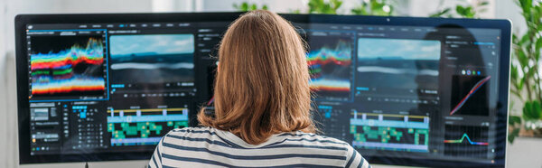 panoramic shot of editor working near computer monitors 