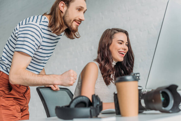 молодые художники улыбаются рядом с цифровой камерой и бумажной чашкой
 