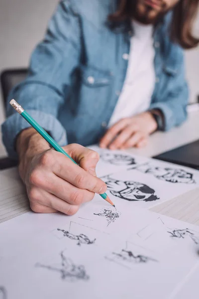 stock image cropped view of illustrator drawing cartoon sketches on paper 