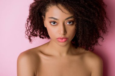 Pembe üzerine güzel, ciddi, çıplak, Afro-Amerikalı bir kızın portresi.