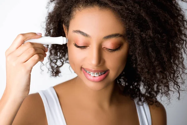 Chica Afroamericana Sonriente Con Frenos Dentales Usando Rodillo Ojo Hidratante — Foto de Stock