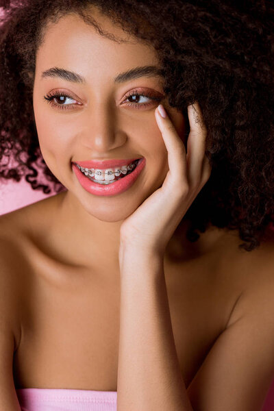 happy attractive african american girl with dental braces, isolated on pink