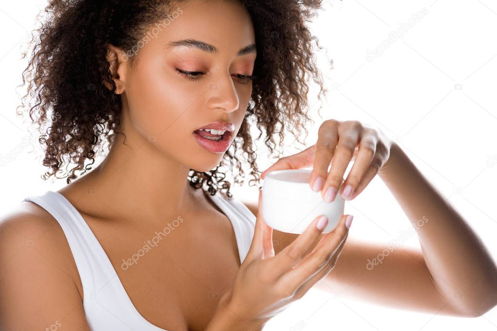 african american girl with perfect skin holding plastic container with face cream, isolated on white