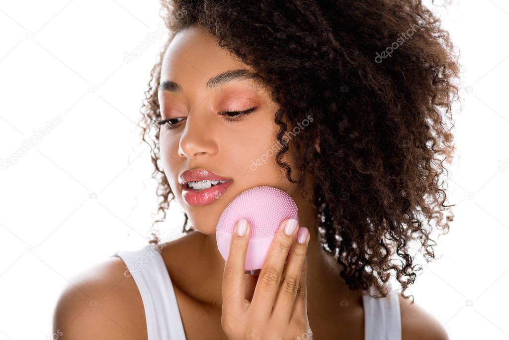 beautiful african american girl using silicone cleansing facial brush, isolated on white