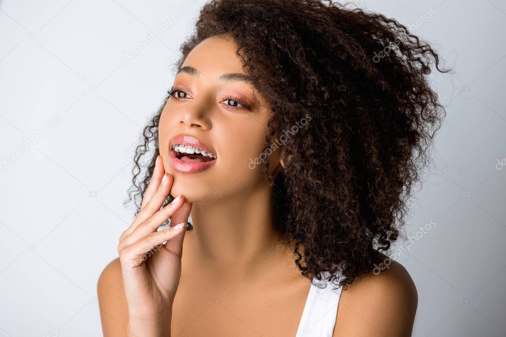 cheerful african american girl with dental braces, isolated on grey