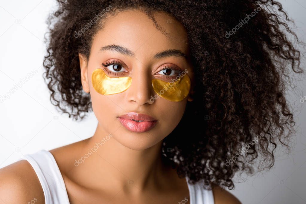 beautiful curly african american girl with golden eye patches, isolated on grey