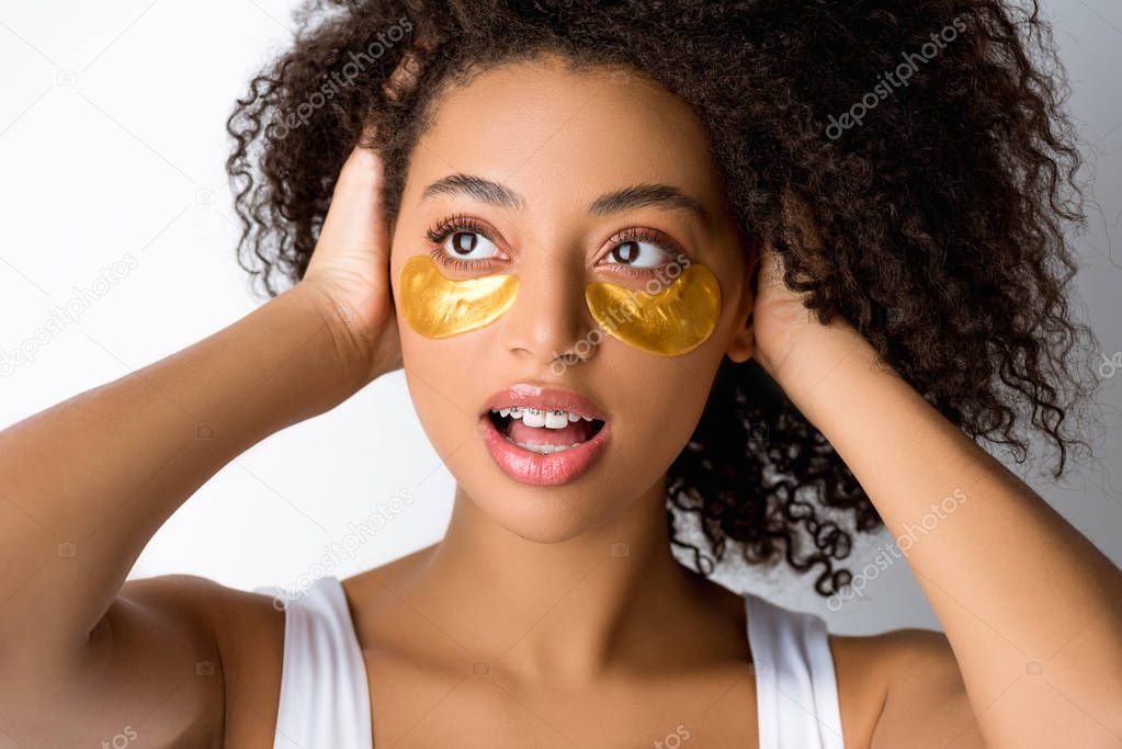 shocked african american girl with golden eye patches, isolated on grey