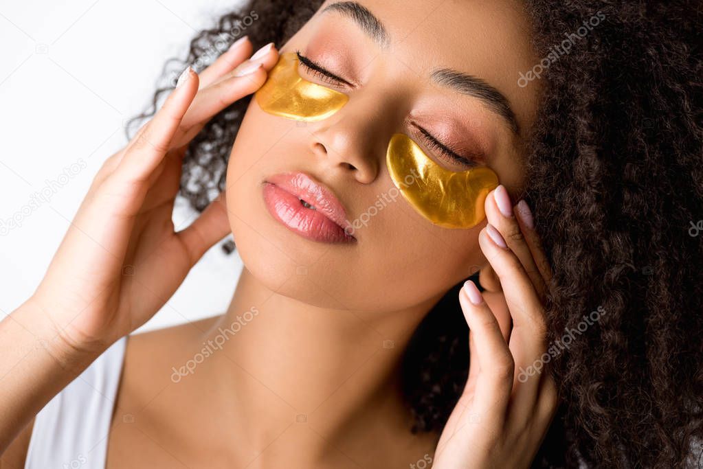 attractive african american girl with golden eye patches and closed eyes, isolated on grey