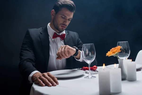 Bonito Homem Olhando Para Relógio Pulso Enquanto Sentado Mesa Servida — Fotografia de Stock