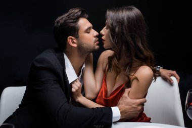 Siyah üzerine izole edilmiş romantik yemek sırasında birbirine bakan zarif çiftin yan görüntüsü.