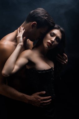 Siyah korseli seksi kız arkadaşına dokunan kaslı bir adam.