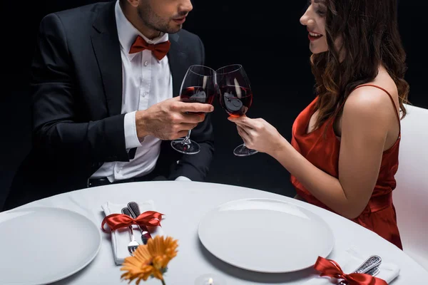 雅致情侣与红酒在与黑色隔离的餐桌旁的侧视图 — 图库照片