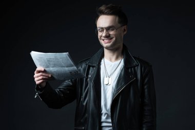 Siyahların üzerine izole edilmiş iş gazetesiyle motosiklet ceketli, güler yüzlü, vahşi adam.
