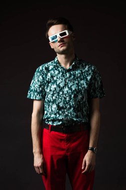 fashionable man in 3d glasses in blue colorful shirt and red pants isolated on black clipart