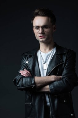 Siyahlar içinde kollarını çapraz bağlamış motorcu ceketli ciddi stil sahibi vahşi bir adam.